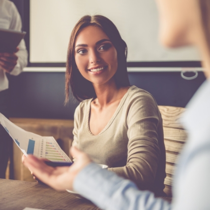 a woman discussing with colleagues while holding papers