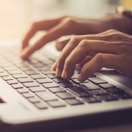 hands typing over a laptop keyboard